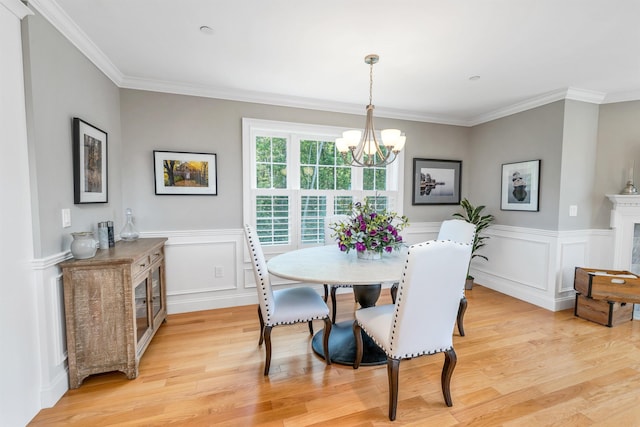 61 Acadia Ln Unit 309, Exeter, NH 03833 - dining area with a chandelier, light wood finished floors, ornamental molding, a wainscoted wall, and a premium fireplace