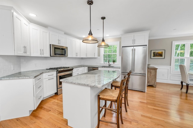 61 Acadia Ln Unit 309, Exeter, NH 03833 - kitchen with appliances with stainless steel finishes, light wood-style flooring, a kitchen bar, white cabinetry, and a kitchen island