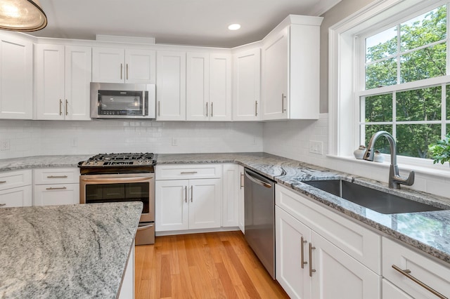 61 Acadia Ln Unit 309, Exeter, NH 03833 - kitchen featuring appliances with stainless steel finishes, healthy amount of natural light, white cabinetry, backsplash, and recessed lighting