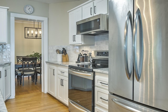 67 Pine Ave, Keene, NH 03431 - kitchen featuring appliances with stainless steel finishes, a chandelier, decorative backsplash, and white cabinetry