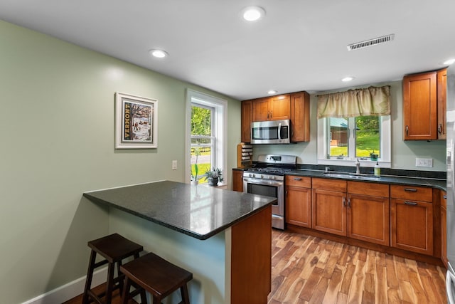 450 Ryan Rd, Duxbury, VT 05676 - kitchen with stainless steel appliances, dark countertops, a kitchen bar, brown cabinetry, and recessed lighting