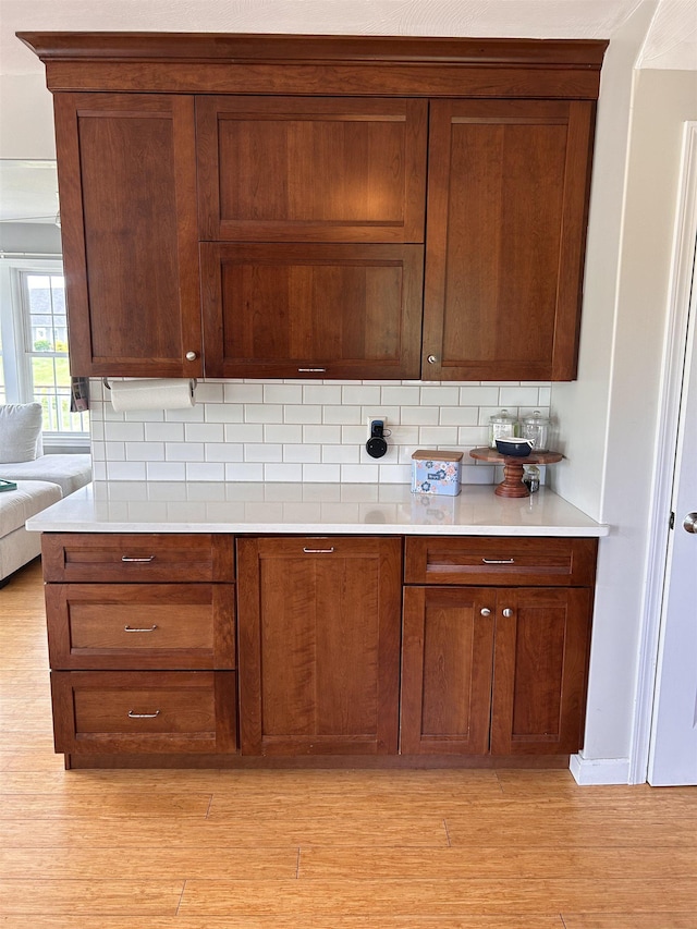 81 Cider St, Epping, NH 03042 - kitchen with decorative backsplash, light countertops, light wood-type flooring, and brown cabinets