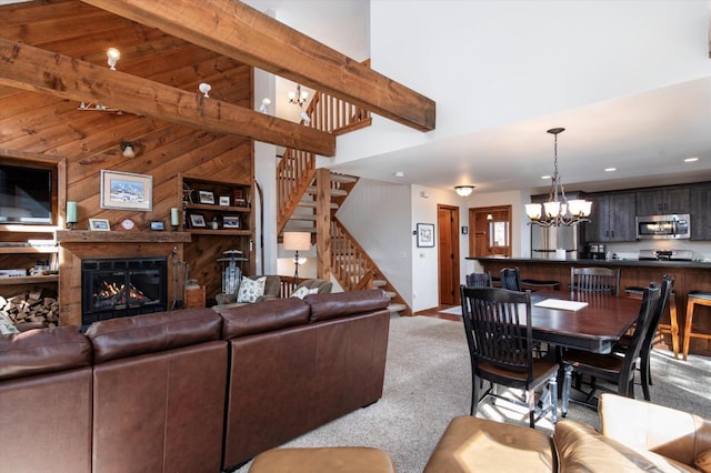 36 Lower Iv Unit 48A, Ludlow, VT 05149 - living room featuring carpet, a chandelier, stairway, wood walls, and a glass covered fireplace