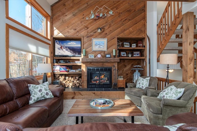36 Lower Iv Unit 48A, Ludlow, VT 05149 - living area featuring healthy amount of natural light, a towering ceiling, wooden walls, a glass covered fireplace, and stairs