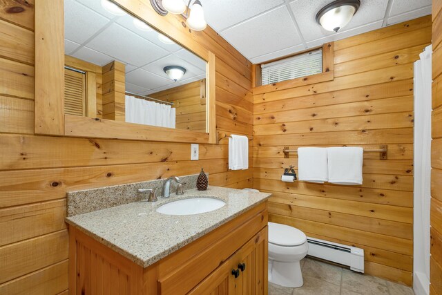 203 Orris Rd, Thornton, NH 03285 - bathroom with a baseboard radiator, a drop ceiling, vanity, tile patterned floors, and wood walls