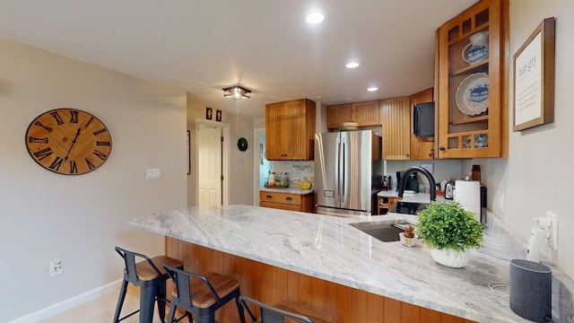 501 Bean Hill Rd Unit 32, Northfield, NH 03276 - kitchen with freestanding refrigerator, a peninsula, brown cabinets, light stone counters, and recessed lighting