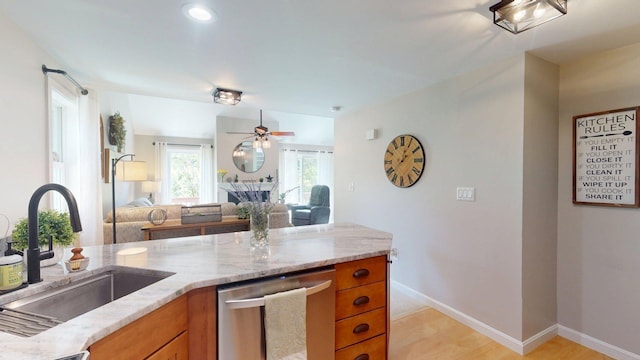 501 Bean Hill Rd Unit 32, Northfield, NH 03276 - kitchen featuring stainless steel dishwasher, brown cabinetry, light stone counters, and open floor plan