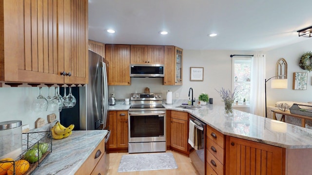 501 Bean Hill Rd Unit 32, Northfield, NH 03276 - kitchen featuring appliances with stainless steel finishes, a peninsula, light stone counters, glass insert cabinets, and brown cabinets