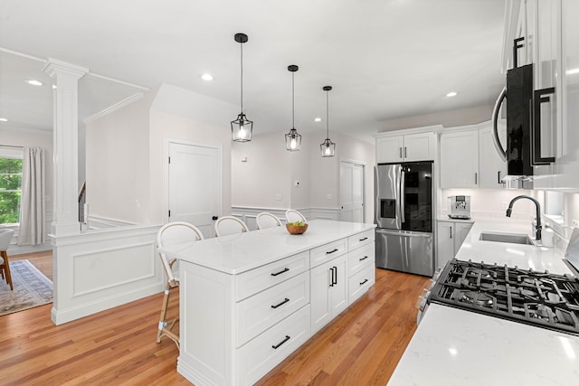 9 Bonanno Rd, Salem, NH 03079 - kitchen featuring stainless steel appliances, a kitchen breakfast bar, light wood-style floors, white cabinets, and a wainscoted wall