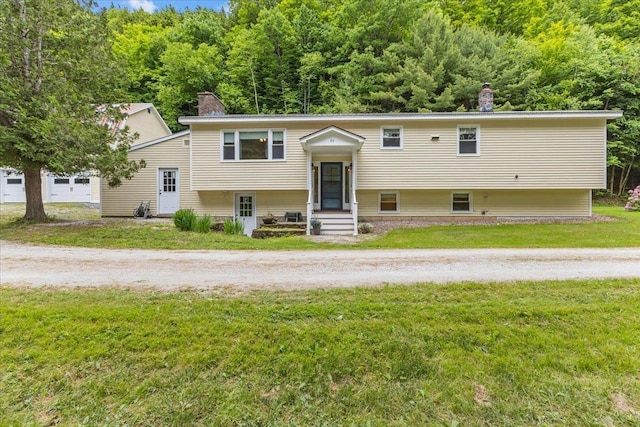 89 Catella Rd, Essex, VT 05452 - bi-level home featuring a chimney, a front lawn, a wooded view, and entry steps