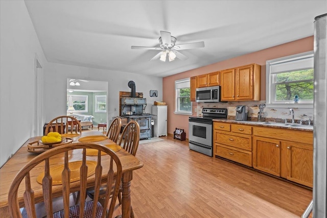 89 Catella Rd, Essex, VT 05452 - kitchen featuring stainless steel appliances, a wood stove, ceiling fan, backsplash, and light wood-style flooring