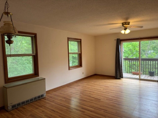 122 Batchelder St Unit A-8, Barre City, VT 05641 - empty room with radiator heating unit, ceiling fan, wood finished floors, and a textured ceiling