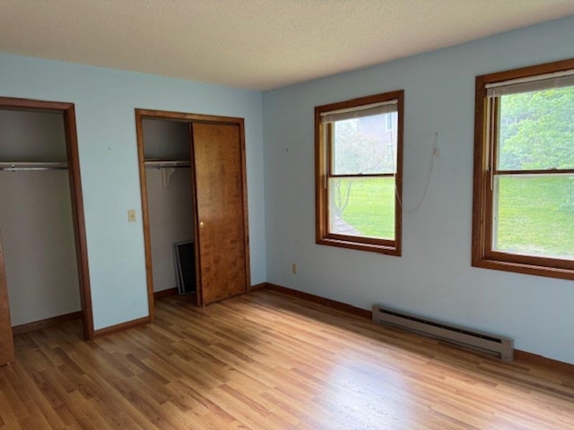 122 Batchelder St Unit A-8, Barre City, VT 05641 - unfurnished bedroom with a baseboard heating unit, multiple closets, light wood finished floors, and multiple windows