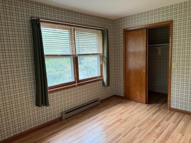 122 Batchelder St Unit A-8, Barre City, VT 05641 - unfurnished bedroom with baseboard heating, light wood finished floors, a closet, and wallpapered walls