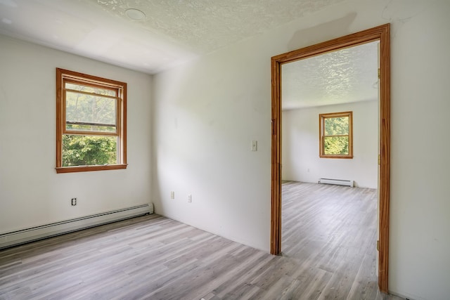945 Mason Rd, Wilton, NH 03086 - spare room featuring a textured ceiling, wood finished floors, and a baseboard heating unit
