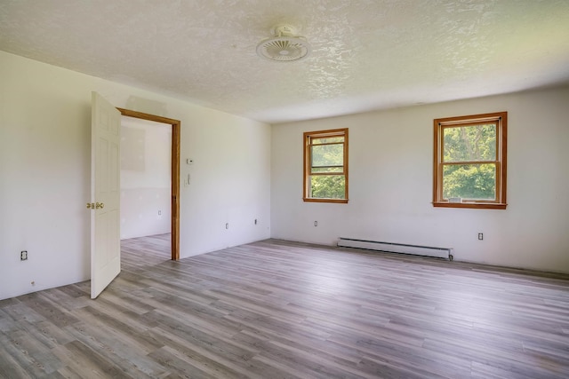 945 Mason Rd, Wilton, NH 03086 - empty room with a baseboard radiator, wood finished floors, and a textured ceiling