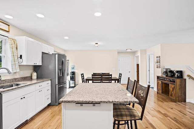 121 Deer Run Rd, Middleton, NH 03887 - kitchen featuring stainless steel fridge, a breakfast bar, a kitchen island, light wood-style flooring, and white cabinetry
