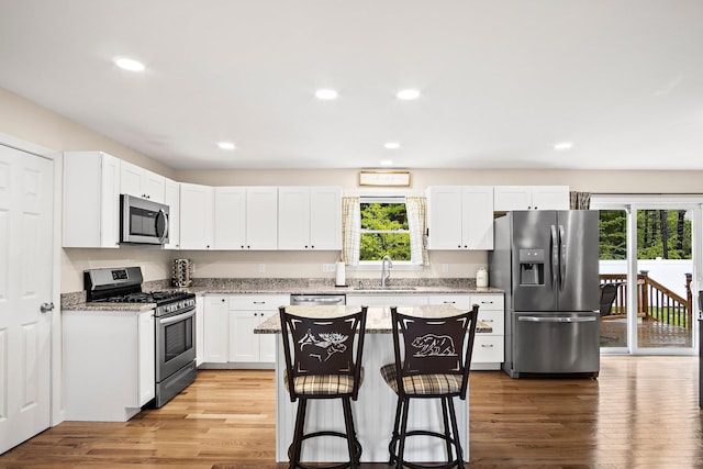 121 Deer Run Rd, Middleton, NH 03887 - kitchen with appliances with stainless steel finishes, a breakfast bar, white cabinetry, a center island, and light wood-style floors