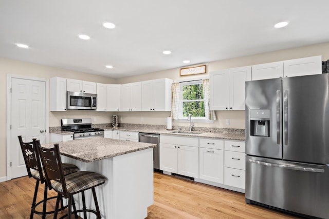 121 Deer Run Rd, Middleton, NH 03887 - kitchen featuring appliances with stainless steel finishes, a kitchen bar, white cabinetry, a center island, and light wood finished floors