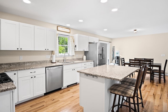 121 Deer Run Rd, Middleton, NH 03887 - kitchen with stainless steel appliances, a breakfast bar, a kitchen island, white cabinets, and light wood-style flooring