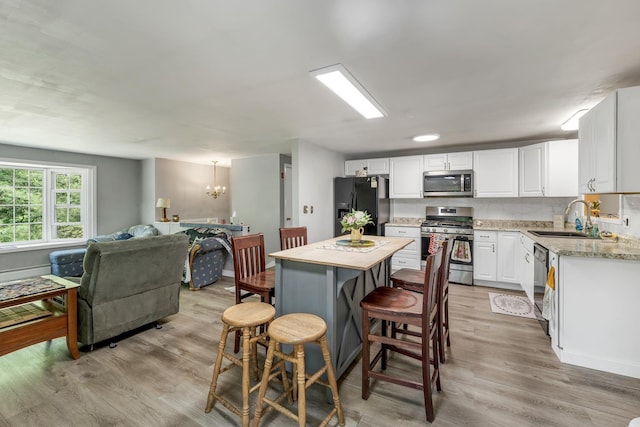 73 Tall Pine Rd, Farmington, NH 03835 - kitchen featuring black appliances, a chandelier, light wood-type flooring, and white cabinetry