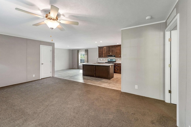 106 Stevens Rd Unit 1, Effingham, NH 03882 - kitchen featuring dark brown cabinetry, a center island with sink, a ceiling fan, open floor plan, and light carpet