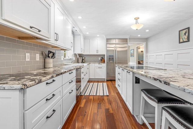 65 Forest St, Londonderry, NH 03053 - kitchen with appliances with stainless steel finishes, dark wood finished floors, white cabinets, decorative backsplash, and light stone counters