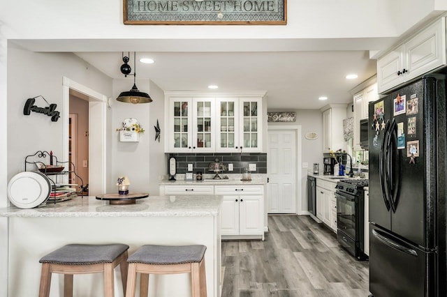 57 Rutland St, Dover, NH 03820 - kitchen featuring black appliances, white cabinets, a breakfast bar, decorative backsplash, and recessed lighting