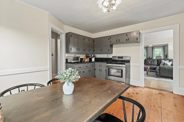 261 Main Ave, South Hampton, NH 03827 - kitchen featuring stainless steel gas range, gray cabinetry, dark countertops, light wood-style floors, and ornamental molding