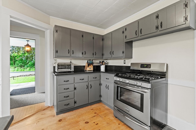 261 Main Ave, South Hampton, NH 03827 - kitchen with stainless steel range with gas stovetop, dark countertops, gray cabinetry, light wood-style flooring, and ornamental molding