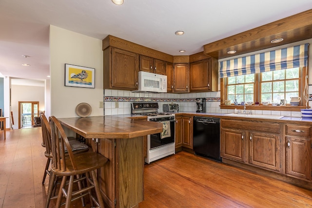 3440 Rte 44, West Windsor, VT 05037 - kitchen with black dishwasher, white microwave, range, a breakfast bar, and backsplash