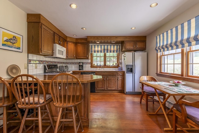3440 Rte 44, West Windsor, VT 05037 - kitchen with white appliances, a peninsula, backsplash, recessed lighting, and a breakfast bar area