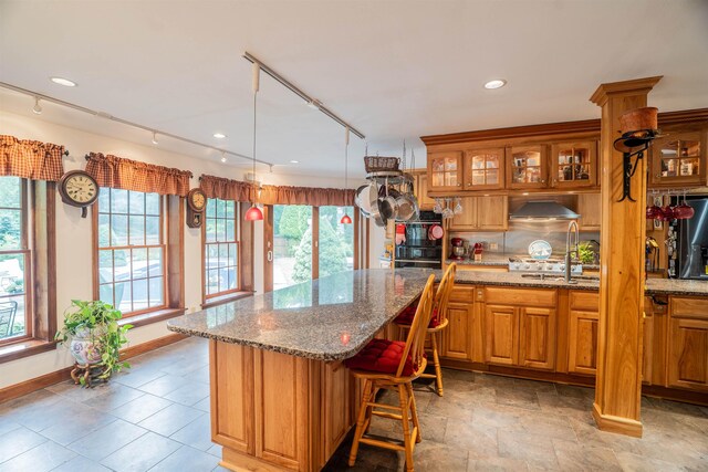 9 Oak Ridge Rd, Kensington, NH 03833 - kitchen with wall chimney range hood, brown cabinets, stone counters, a center island, and recessed lighting