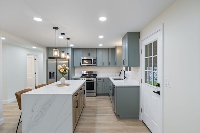 11 Bond St, Hudson, NH 03051 - kitchen with stainless steel appliances, gray cabinetry, a kitchen island, a breakfast bar, and light wood finished floors