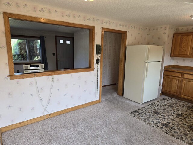 9 Mariette Dr, Portsmouth, NH 03801 - kitchen featuring freestanding refrigerator, wallpapered walls, brown cabinets, light carpet, and heating unit