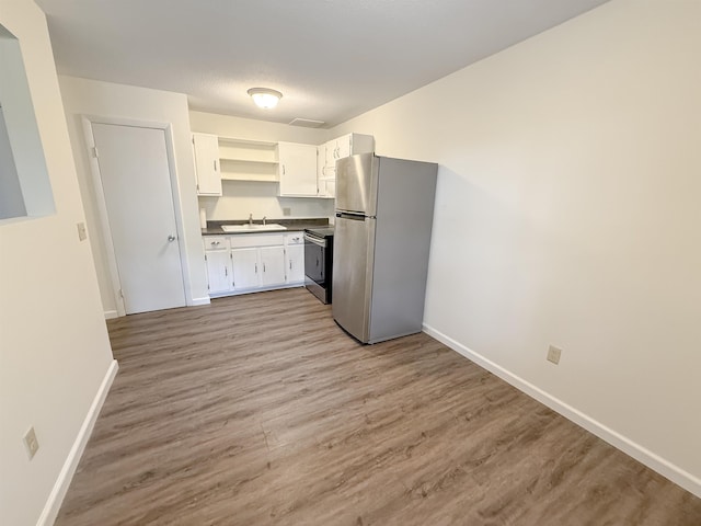 18 Gould Ave Unit 1, Meredith, NH 03253 - kitchen with stainless steel appliances, open shelves, dark countertops, white cabinetry, and light wood-type flooring