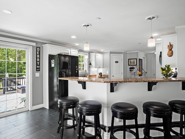 20 Lawrence Rd, Derry, NH 03038 - kitchen with black fridge, a kitchen breakfast bar, white cabinets, healthy amount of natural light, and recessed lighting