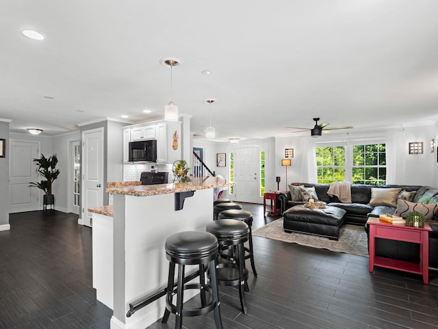20 Lawrence Rd, Derry, NH 03038 - kitchen with black microwave, white cabinets, a kitchen breakfast bar, a ceiling fan, and light stone counters