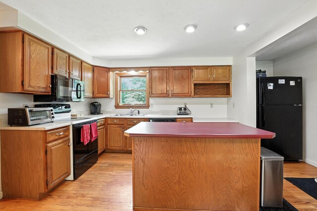 20 Edward Dr, Concord, NH 03301 - kitchen with black appliances, a center island, light wood-type flooring, recessed lighting, and brown cabinets