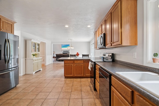 60 Lady Slipper Ln, Chester, NH 03036 - kitchen featuring appliances with stainless steel finishes, dark countertops, brown cabinetry, a peninsula, and light tile patterned flooring