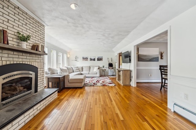 19 Hardwood Rd, Windham, NH 03087 - living room featuring baseboard heating, a brick fireplace, light wood finished floors, a baseboard radiator, and a textured ceiling