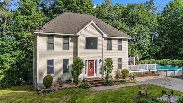 12 Lawrence St, Derry, NH 03038 - colonial home with a front lawn, an outdoor pool, and view of wooded area