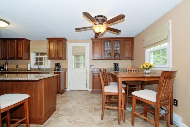 27 Meisner Rd, Salem, NH 03079 - kitchen featuring ceiling fan, glass insert cabinets, light stone countertops, a breakfast bar area, and brown cabinets