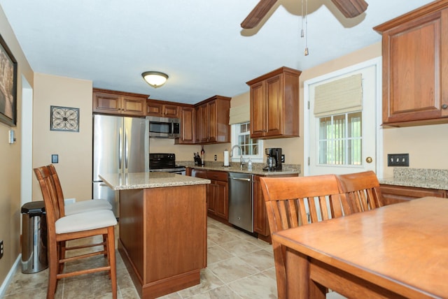 27 Meisner Rd, Salem, NH 03079 - kitchen with stainless steel appliances, a center island, ceiling fan, a kitchen bar, and light stone counters