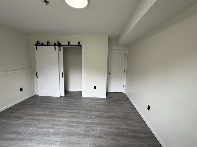 121 Cluff Xing Unit 8, Salem, NH 03079 - unfurnished bedroom featuring a barn door, dark wood finished floors, and a closet