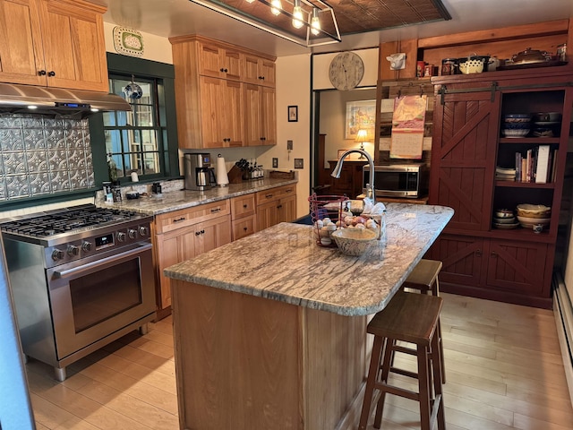 197 Circuit Rd, Ossipee, NH 03864 - kitchen featuring appliances with stainless steel finishes, under cabinet range hood, light wood finished floors, a kitchen bar, and light stone counters