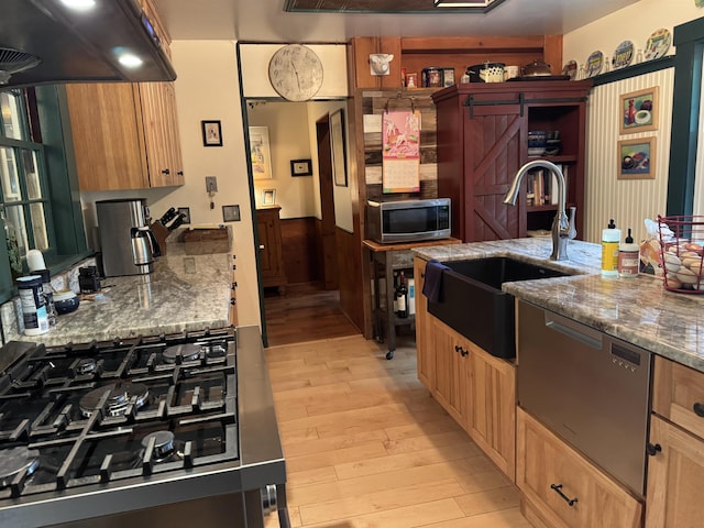 197 Circuit Rd, Ossipee, NH 03864 - kitchen featuring appliances with stainless steel finishes, ventilation hood, light wood finished floors, a wainscoted wall, and stone counters