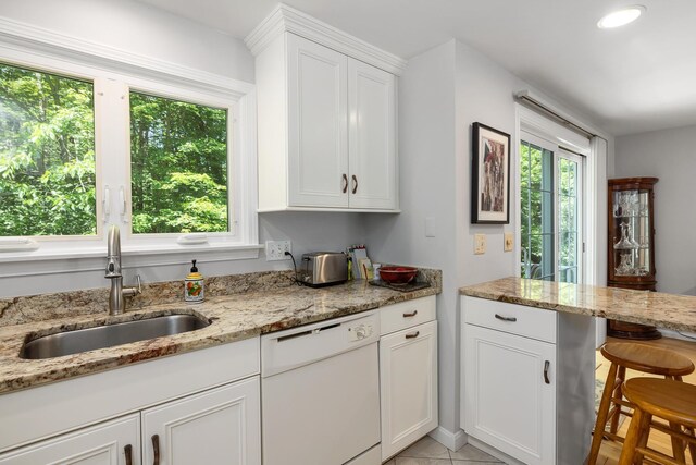 46 Pine Meadows Dr, Exeter, NH 03833 - kitchen featuring dishwasher, white cabinets, light stone countertops, light tile patterned floors, and a kitchen breakfast bar