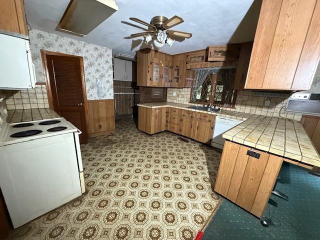 224 E Dunbarton Rd, Goffstown, NH 03045 - kitchen with white appliances, a ceiling fan, tile countertops, wallpapered walls, and wainscoting