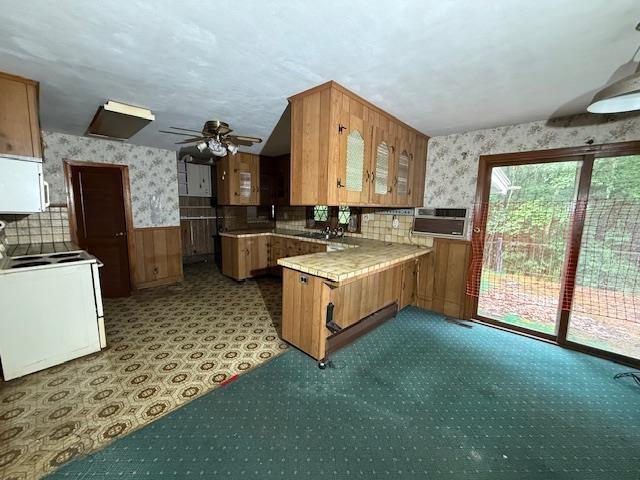 224 E Dunbarton Rd, Goffstown, NH 03045 - kitchen featuring range, wallpapered walls, a peninsula, brown cabinetry, and white microwave